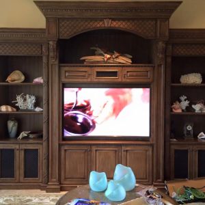 An ornate carved wood entertainment centre housing a television, with display shelves of coral and seashells either side.